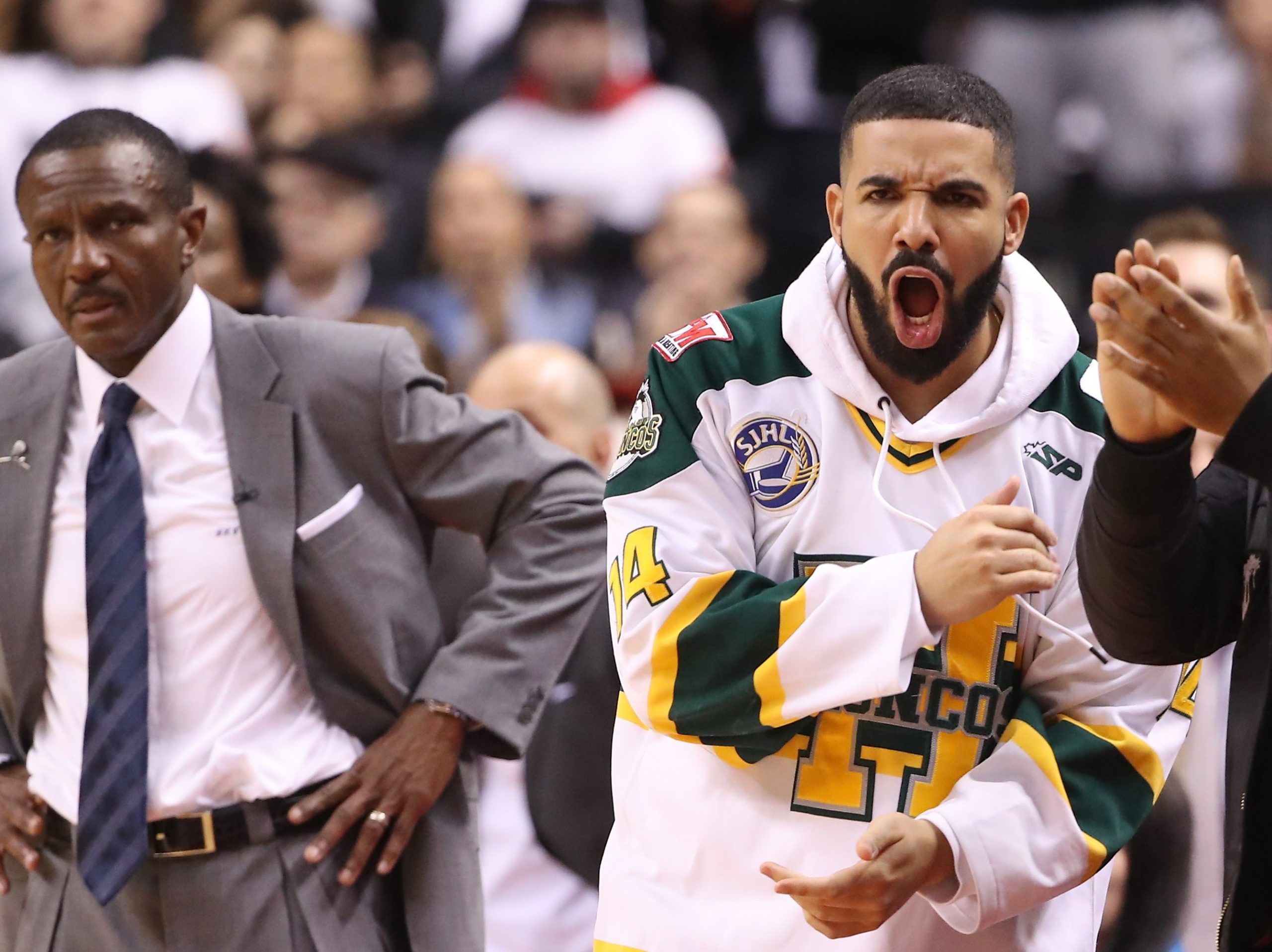 Rap artist Drake celebrates as head coach Dwane Casey of the Toronto Raptors looks on in the closing moments of their victory against the Washington Wizards in the first quarter during Game One of the first round of the 2018 NBA Playoffs at Air Canada Centre on April 14, 2018 in Toronto. (Tom Szczerbowski/Getty Images) Rap artist Drake celebrates as head coach Dwane Casey of the Toronto Raptors looks on in the closing moments of their victory against the Washington Wizards in the first quarter during Game One of the first round of the 2018 NBA Playoffs at Air Canada Centre on April 14, 2018 in Toronto. (Tom Szczerbowski/Getty Images)