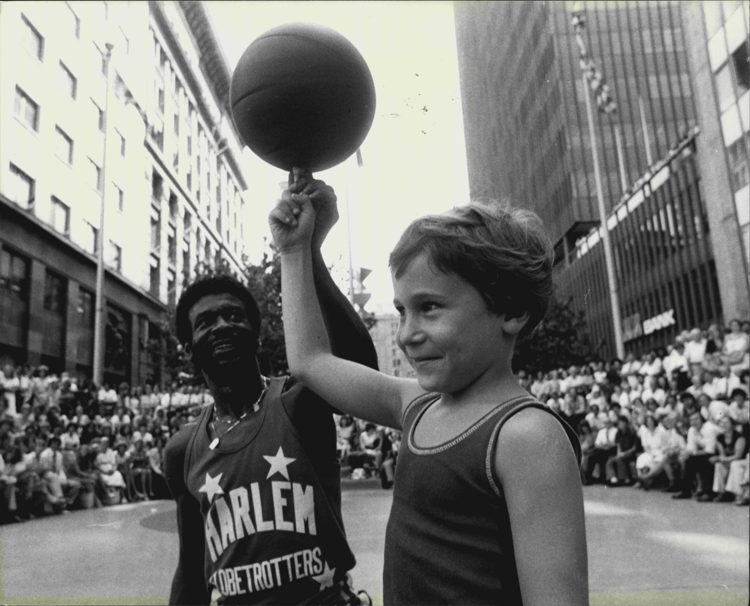 The Harlem Globetrotters at Martin Place Amphitheatre giving a lunch hour display of theur talents.  Julian Cappe, 7, of Bellevue Hill, practices with Larry Rivers one of the Globetrotters. March 3, 1980. (Photo by John Nobley/Fairfax Media).