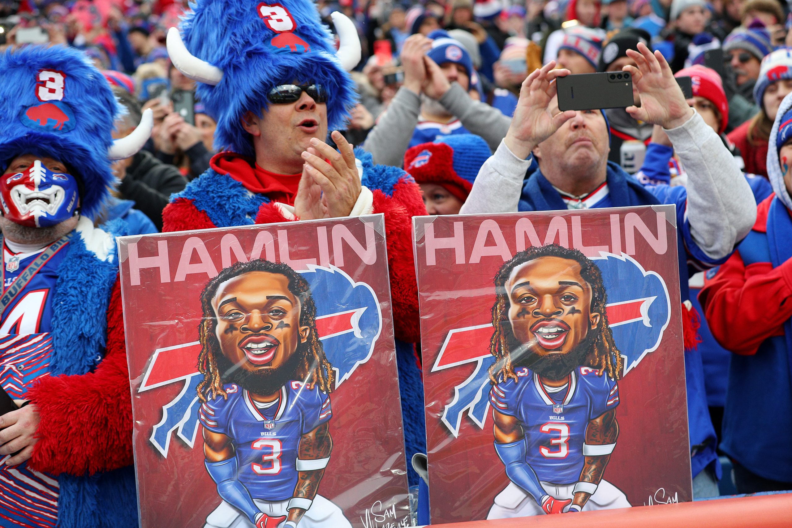 Buffalo Bills fans hold signs in support of Damar Hamlin.