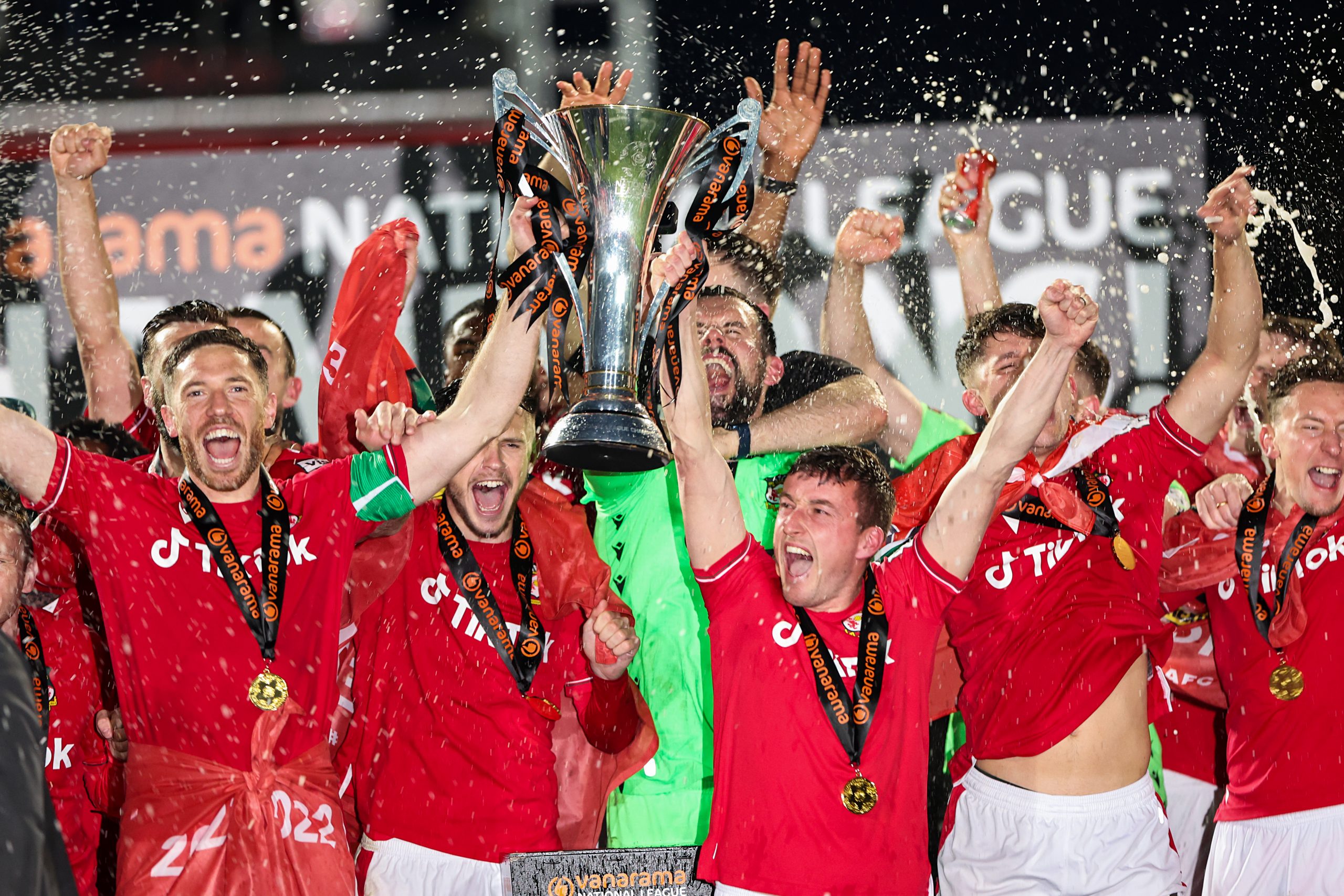 Ben Tozer and Luke Young of Wrexham lift the Vanarama National League Trophy as Wrexham celebrate promotion back to the English Football League during the Vanarama National League match between Wrexham and Boreham Wood at Racecourse Ground on April 22, 2023 in Wrexham, Wales. (Photo by Matthew Ashton - AMA/Getty Images)