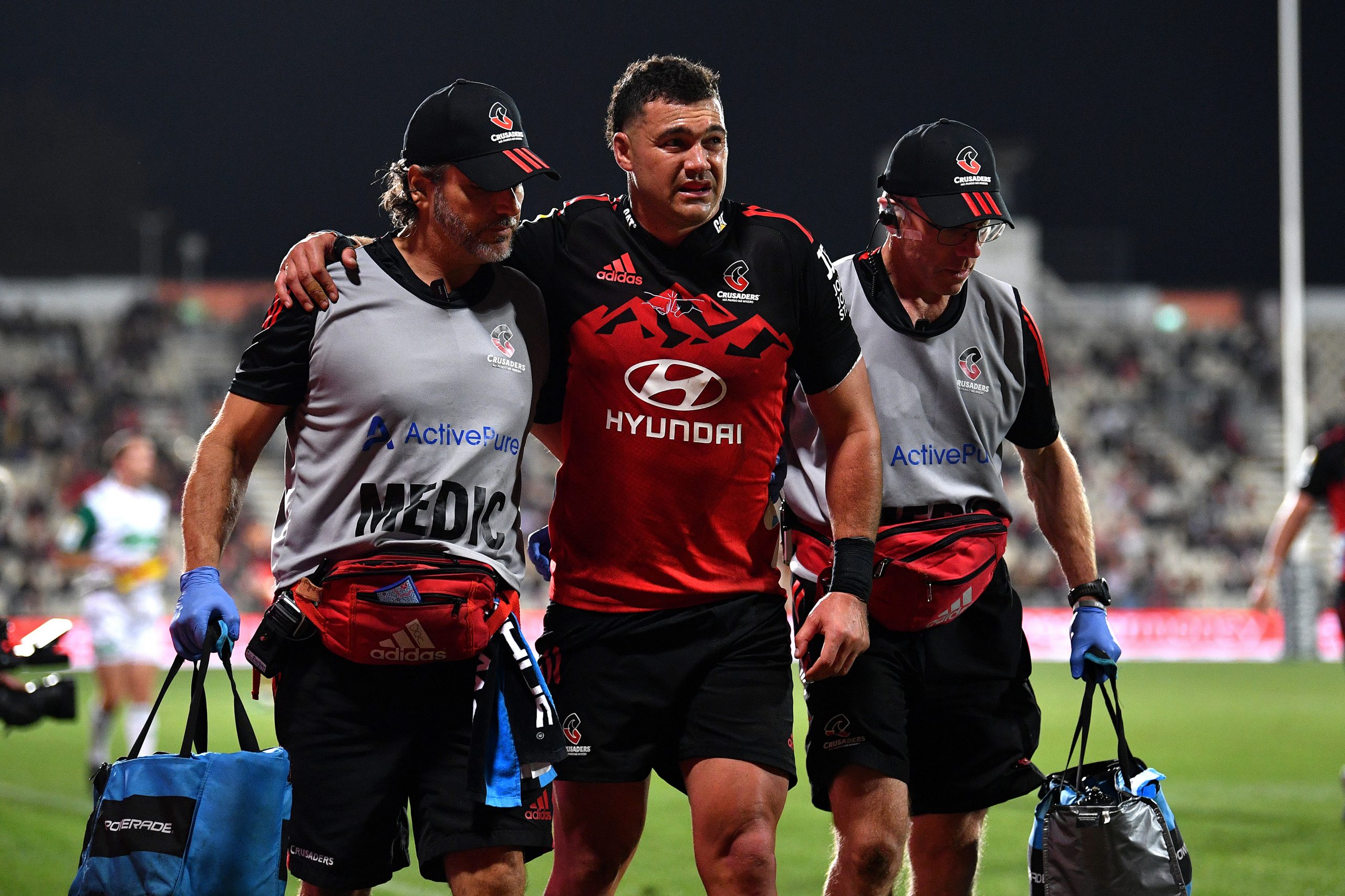 David Havili of the Crusaders is assisted from the field.