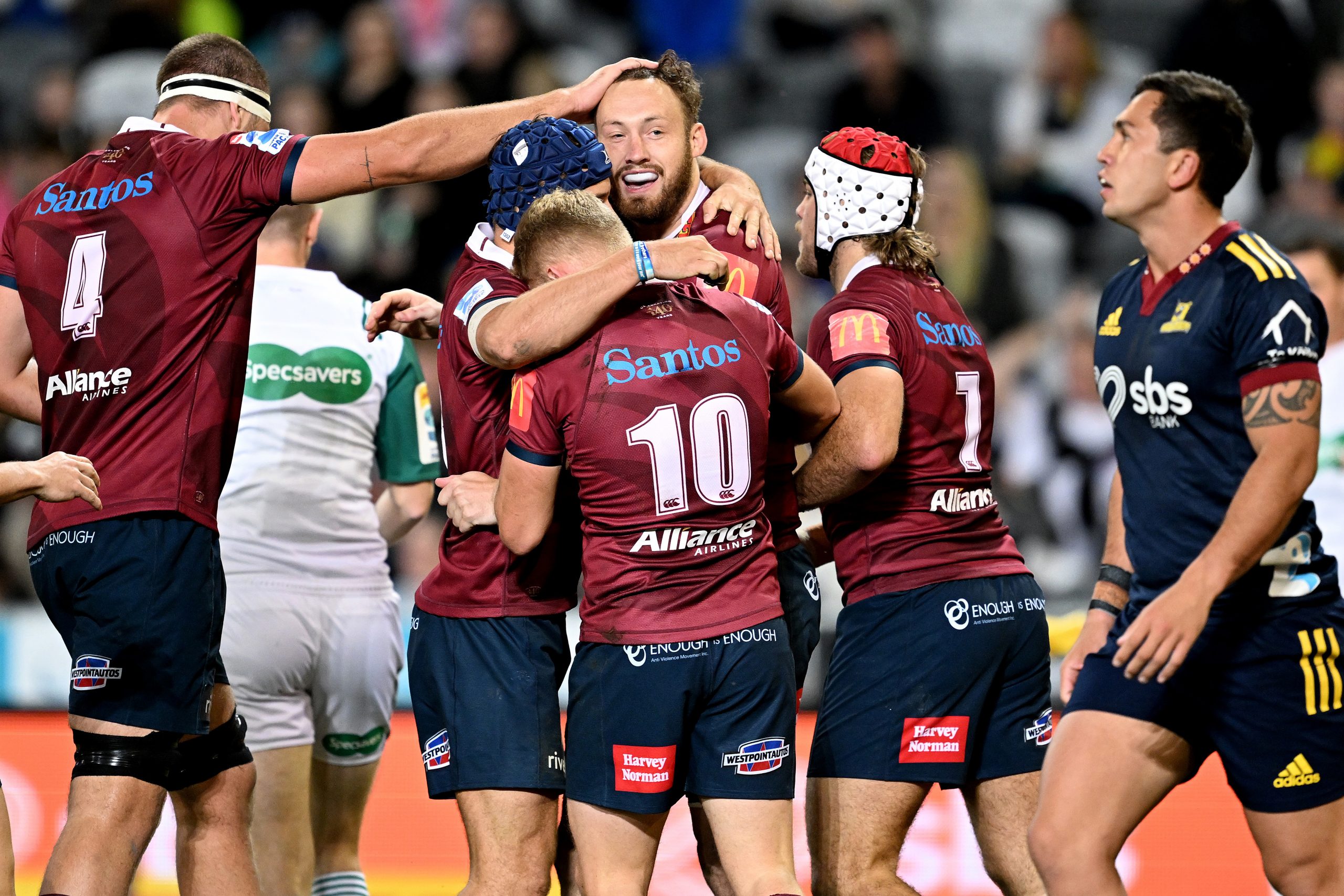 Jake Upfield celebrates with his teammates after scoring a try during the round 14 Super Rugby Pacific match between Highlanders and Queensland Reds.