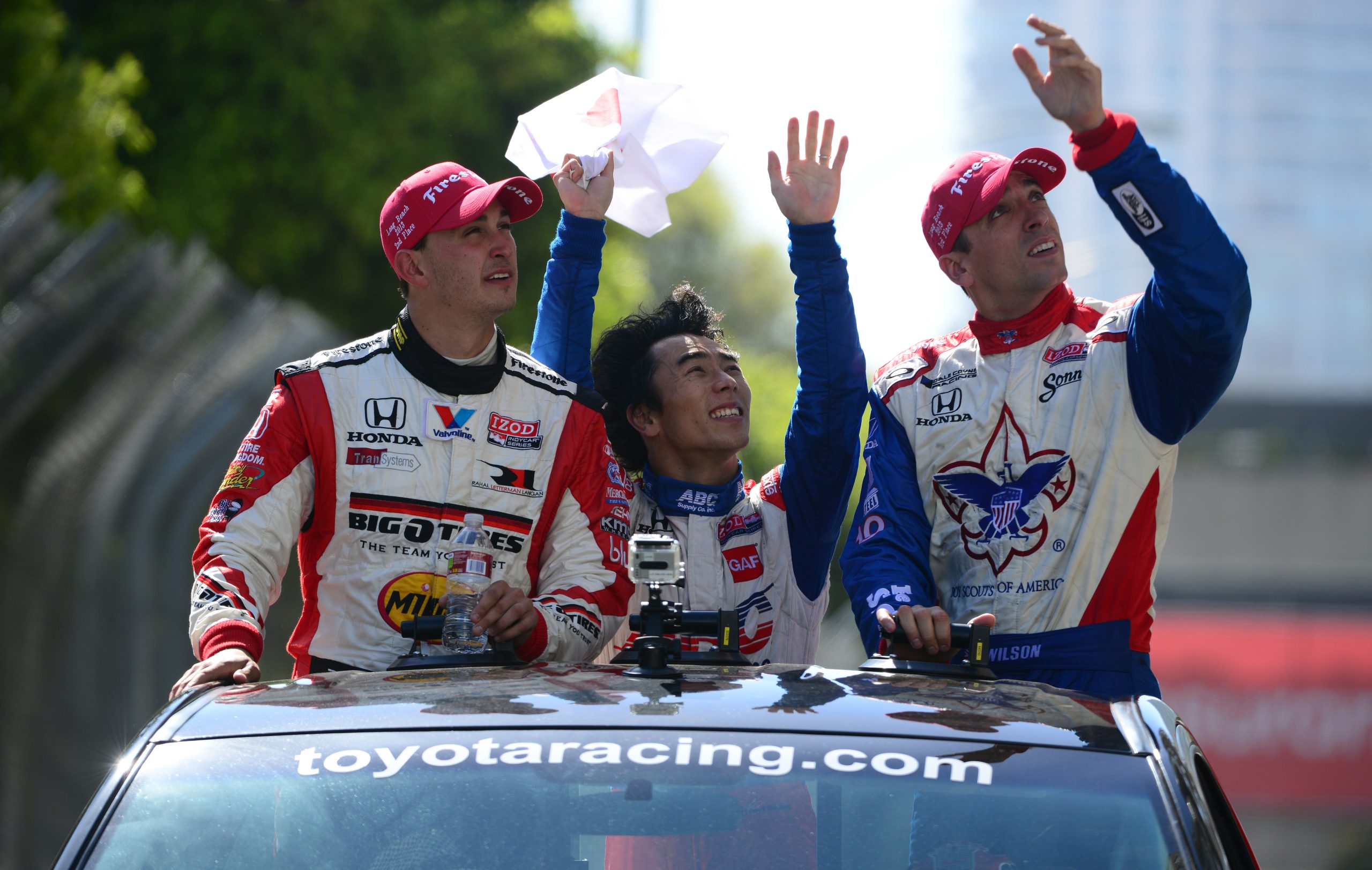 Graham Rahal (left) with Takuma Sato (centre) and Justin Wilson during a driver parade in Long Beach in 2013.