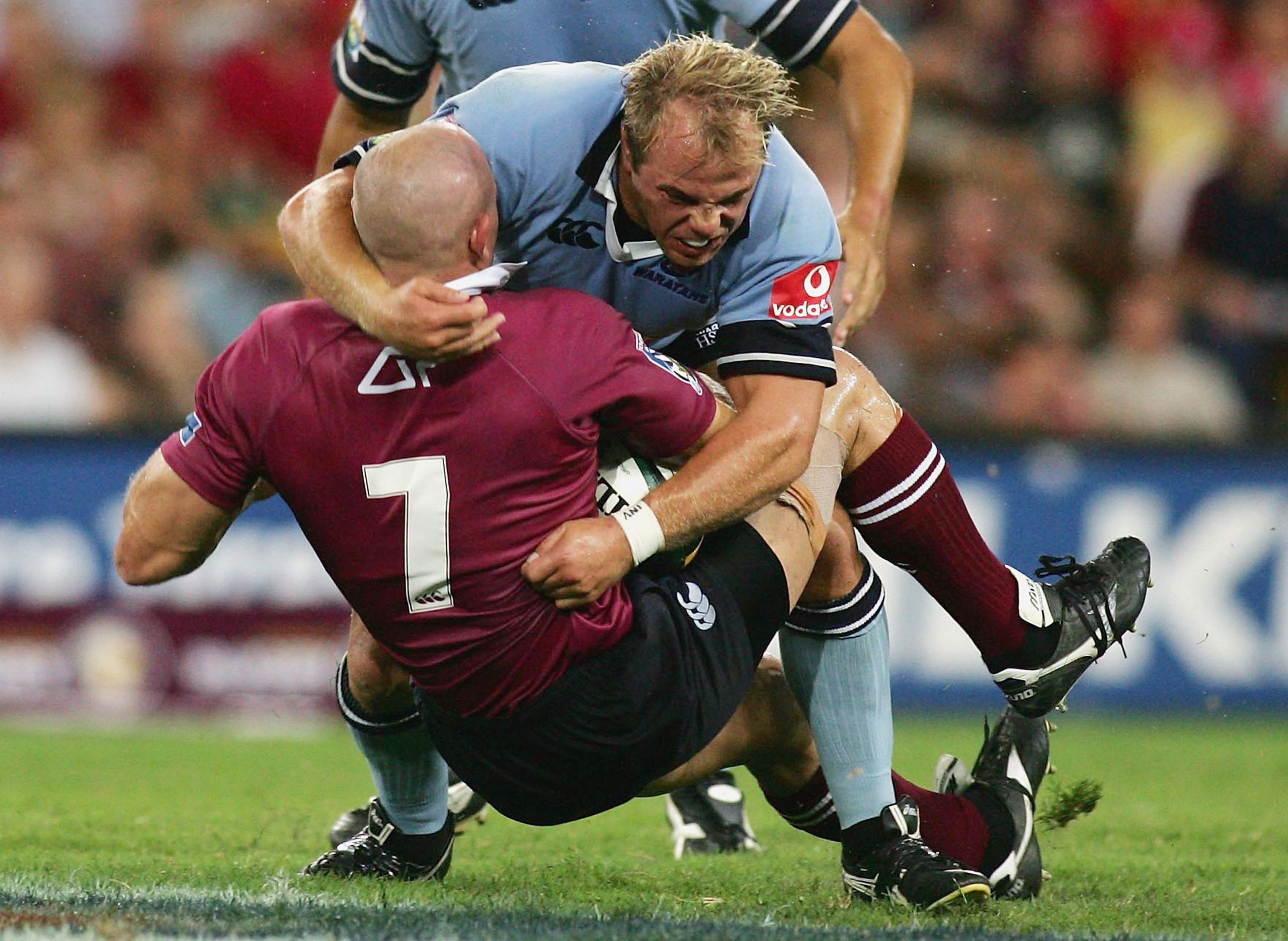 David Croft of the Reds is tackled by Phil Waugh of the Waratahs.