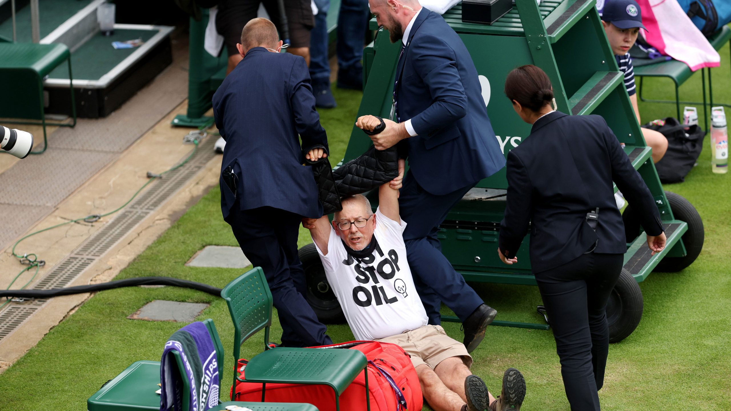 A protester is taken away by security on court 18 after a Just Stop Oil protest during the Women's Singles first round match between Katie Boulter of Great Britain and Daria Saville of Australia during day three of The Championships.