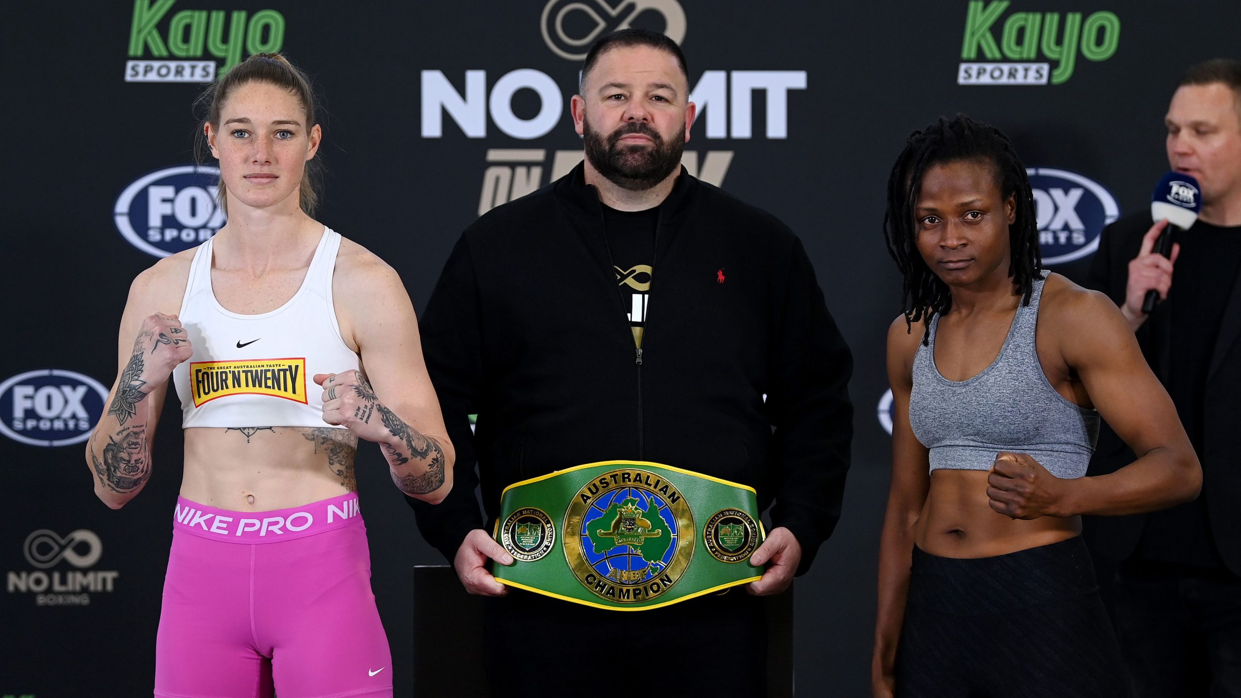 Tayla Harris poses alongside opponent Millicent Agboegbulen a day out from their boxing clash in July, 2023. No Limit CEO George Rose holds the belt they're fighting for.