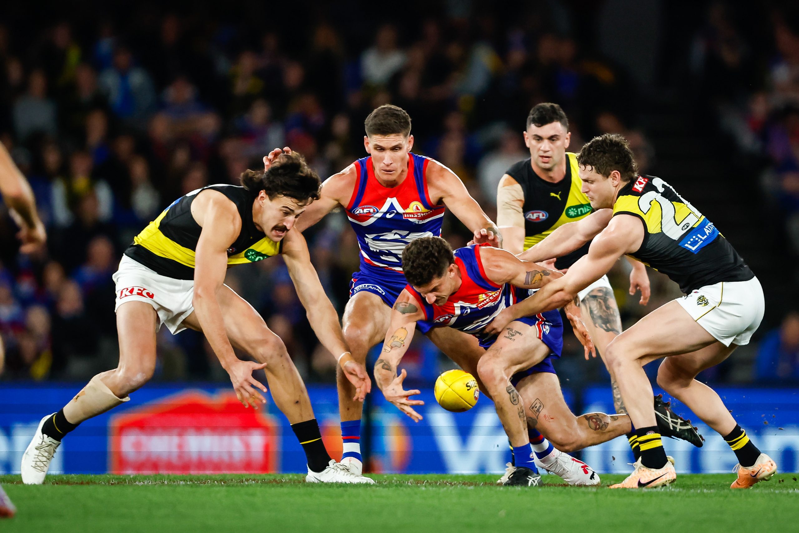 Tom Liberatore of the Bulldogs, and Ivan Soldo and Jacob Hopper of the Tigers compete for the ball during the 2023 AFL round 21 match between the Western Bulldogs and the Richmond Tigers.