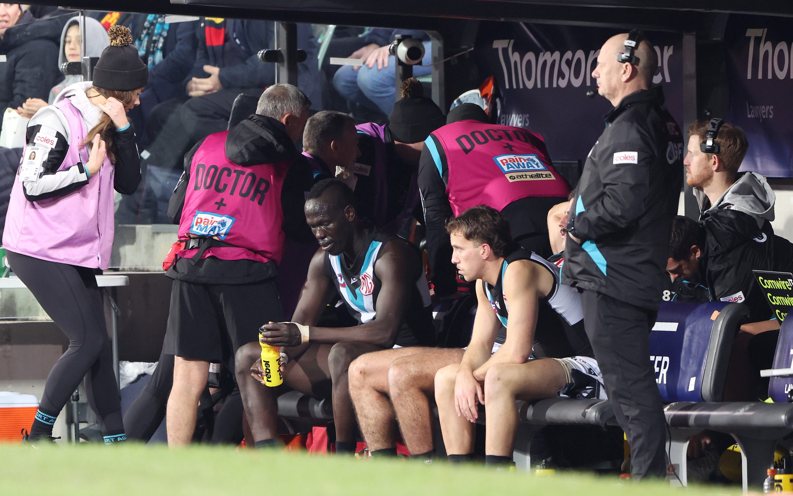 ADELAIDE, AUSTRALIA - JULY 29: Aliir Aliir of the Power on the bench after a collision with Lachie Jones who sits at the back of the bench with the Doctors - Ken Hinkley, Senior Coach of the Power watches the game during the 2023 AFL Round 20 match between the Adelaide Crows and the Port Adelaide Power at Adelaide Oval on July 29, 2023 in Adelaide, Australia. (Photo by Sarah Reed/AFL Photos via Getty Images)