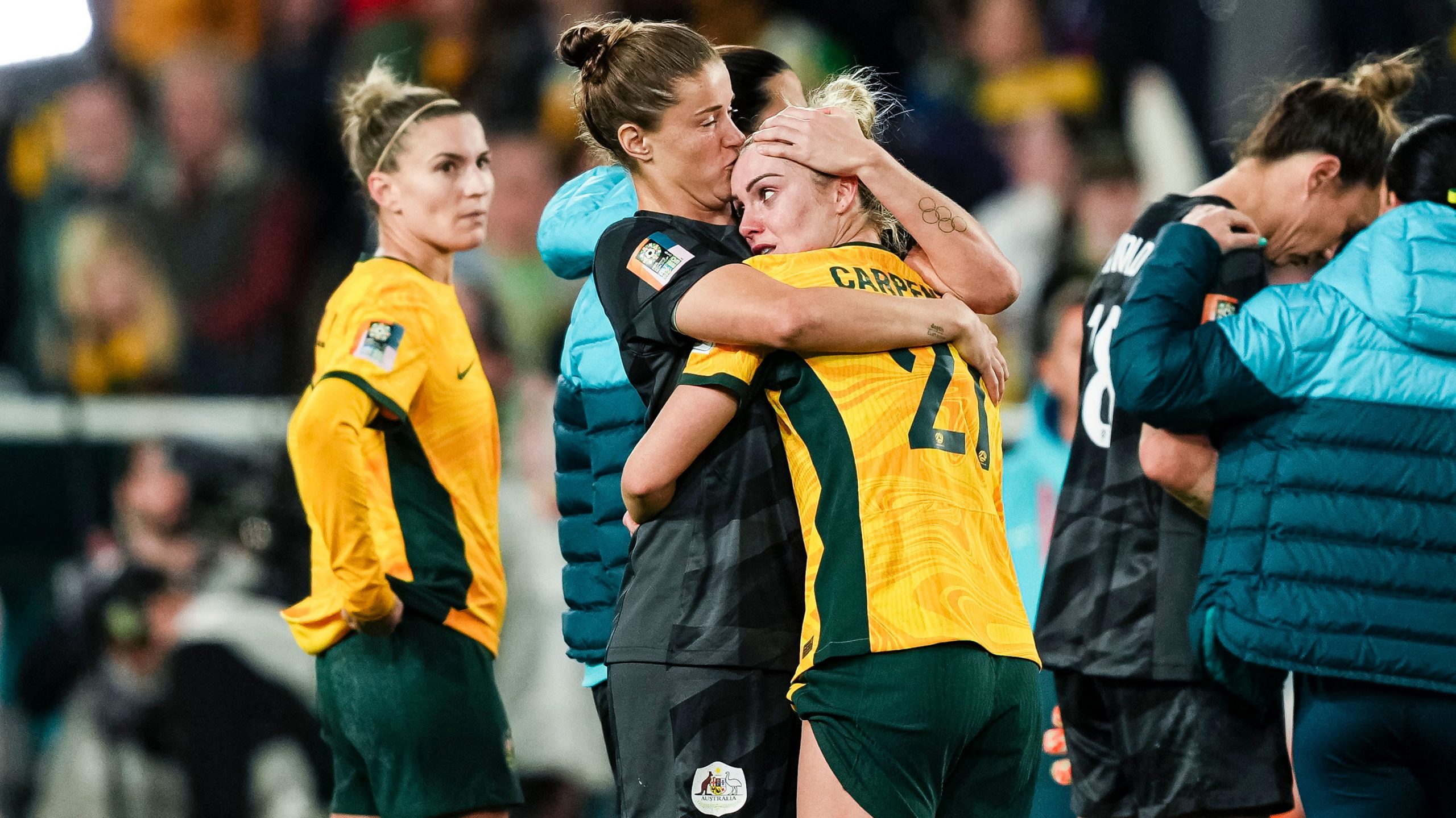 Dejected Matildas star Ellie Carpenter is comforted after Australia's World Cup semi final loss to England.