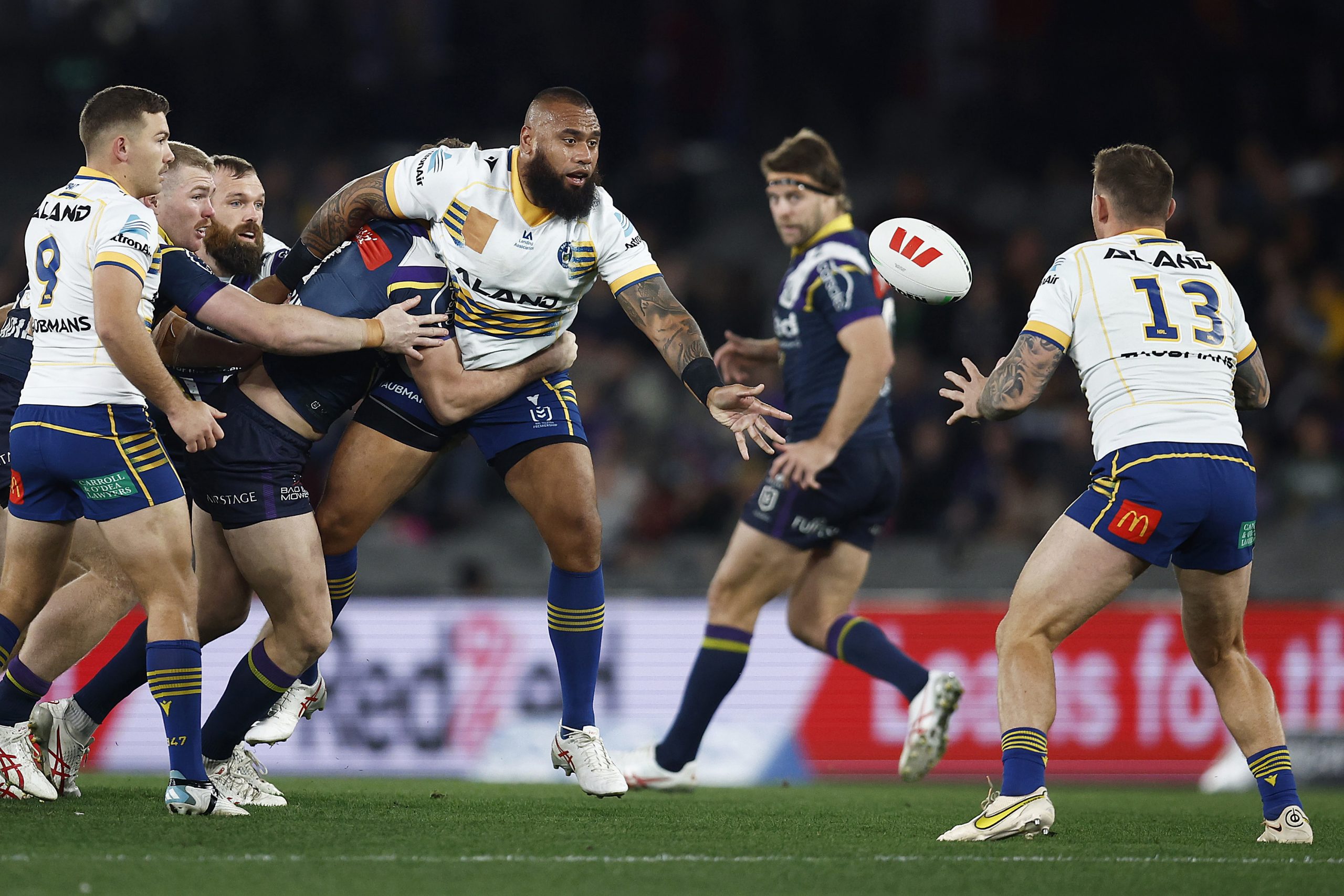 Junior Paulo of the Eels passes the ball whilst being tackled.