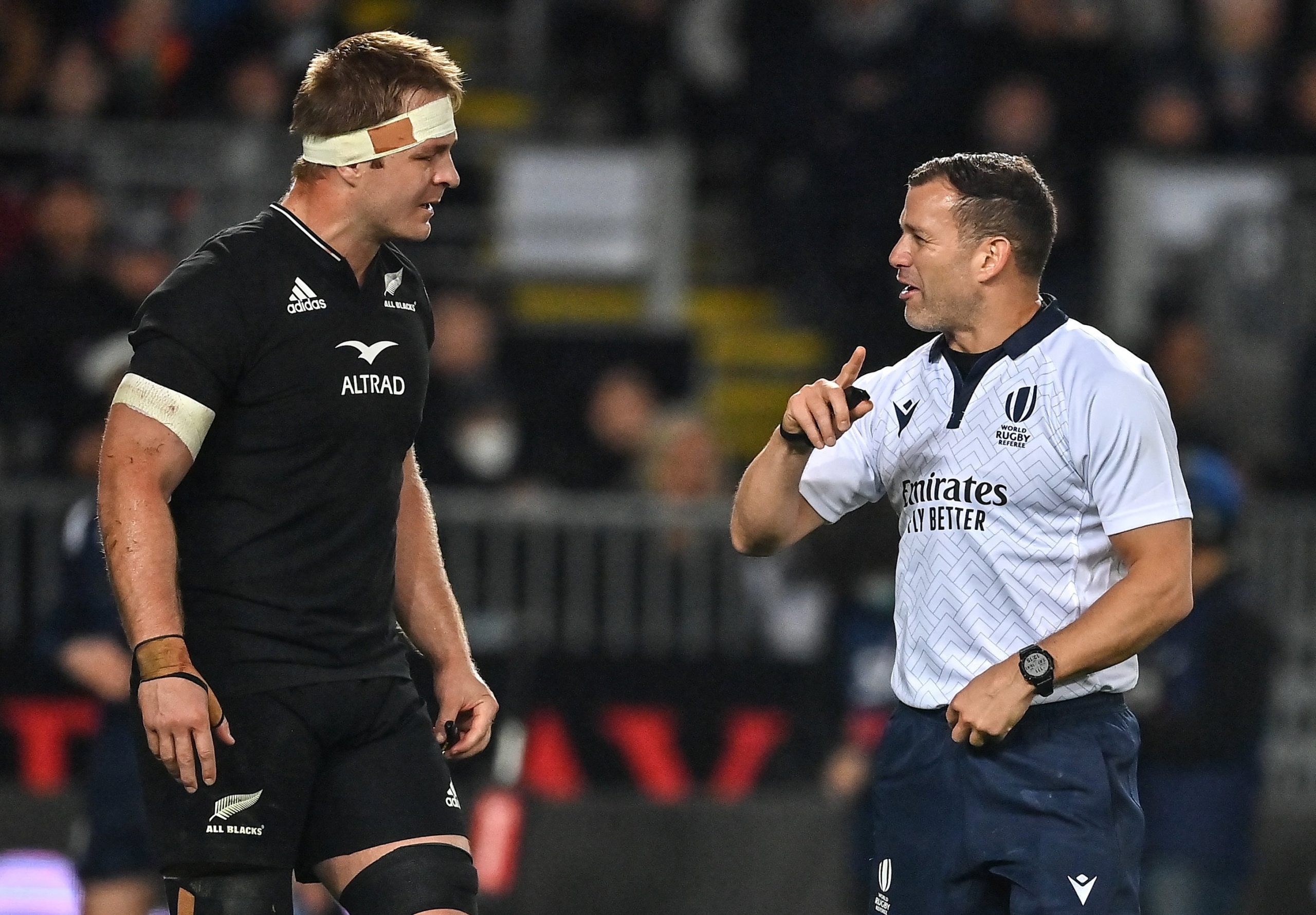 Referee Karl Dickson speaks to New Zealand captain Sam Cane.