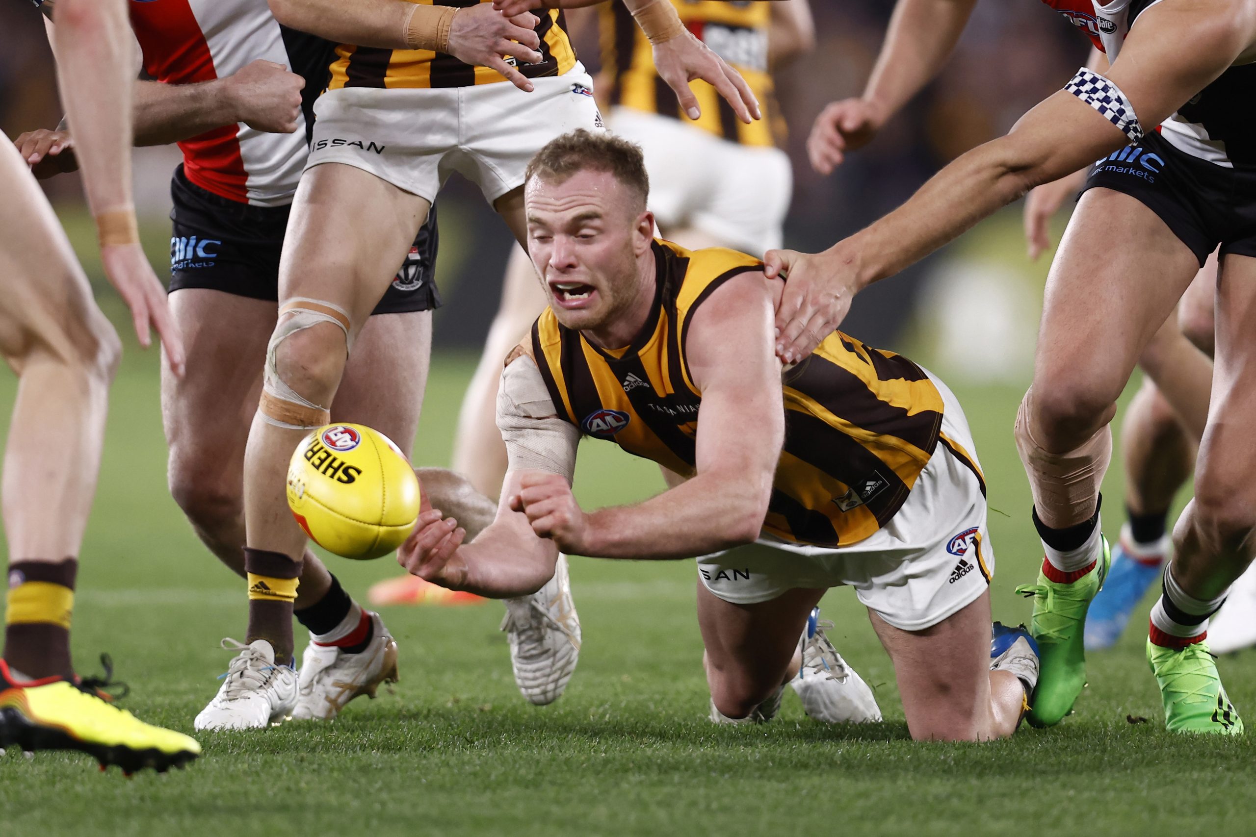 Tom Mitchell shovels a handball in Hawthorn colours.