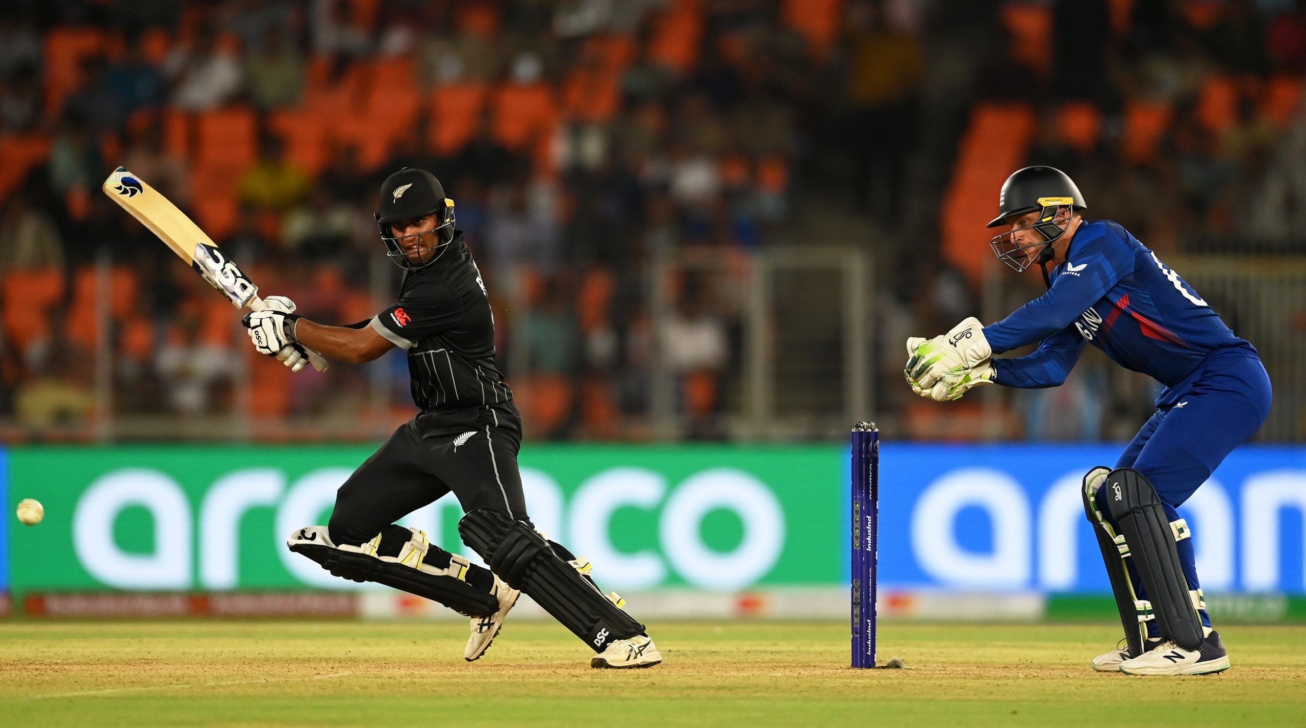 Rachin Ravindra of New Zealand plays a shot as Jos Buttler of England keeps.