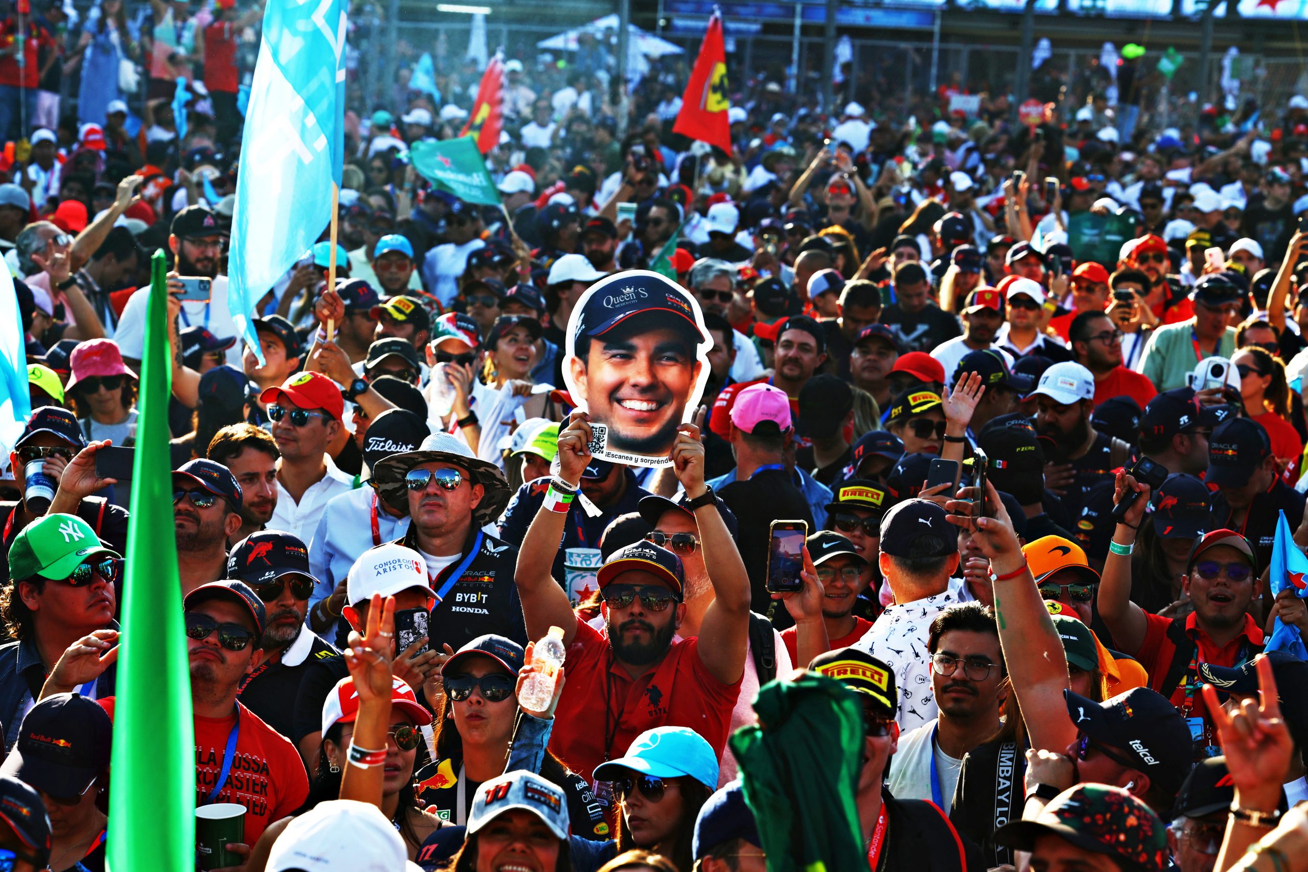 A fan holds up a cardboard cutout of Sergio Perez's head.