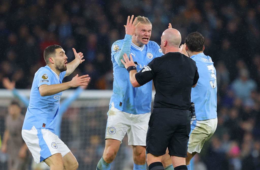 Referee Simon Hooper is surrounded by Erling Haaland, Mateo Kovacic and Ruben Dias.