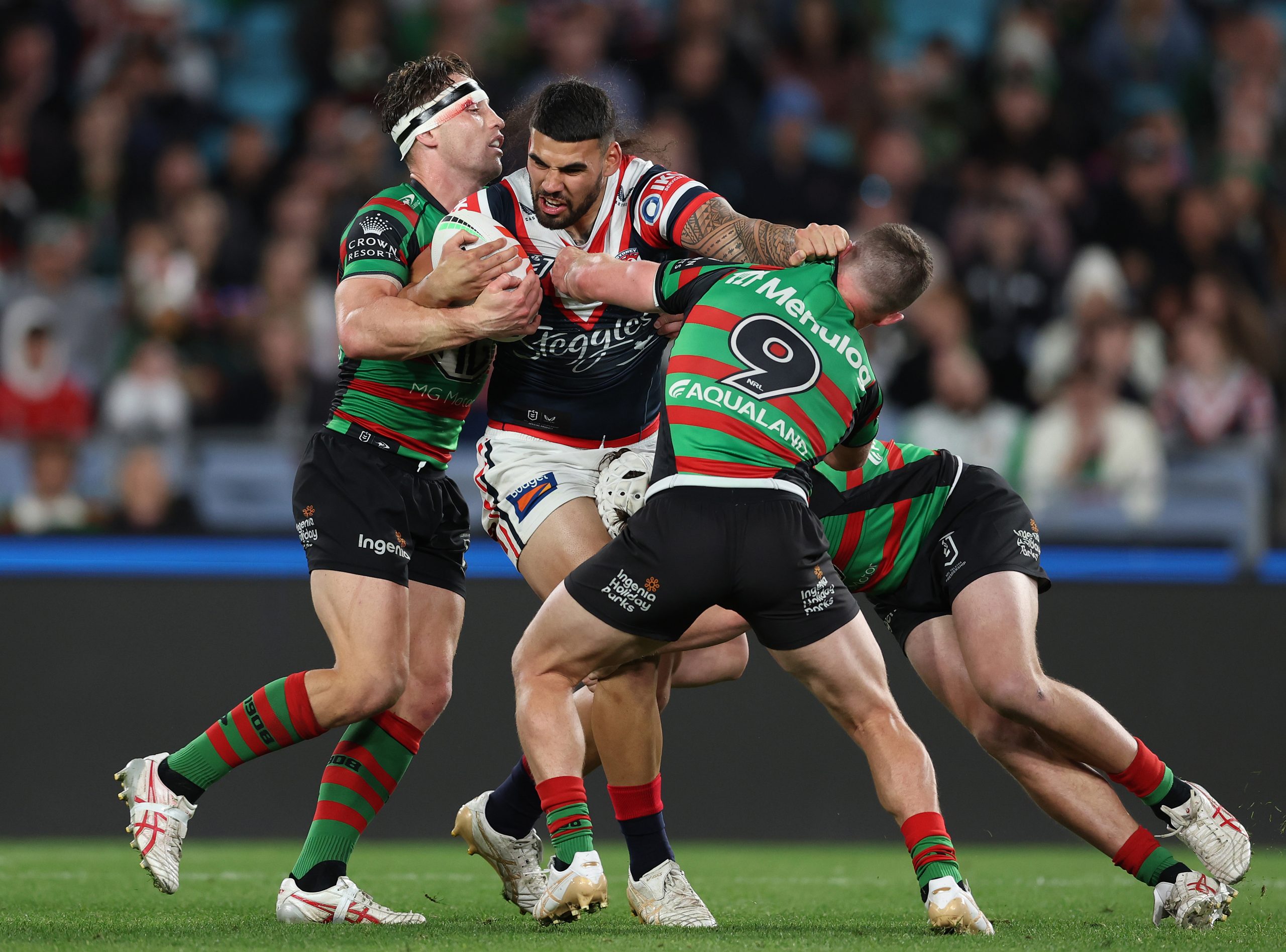 Terrell May of the Roosters attempts to bust through a two-man tackle against the Sydney Roosters. 