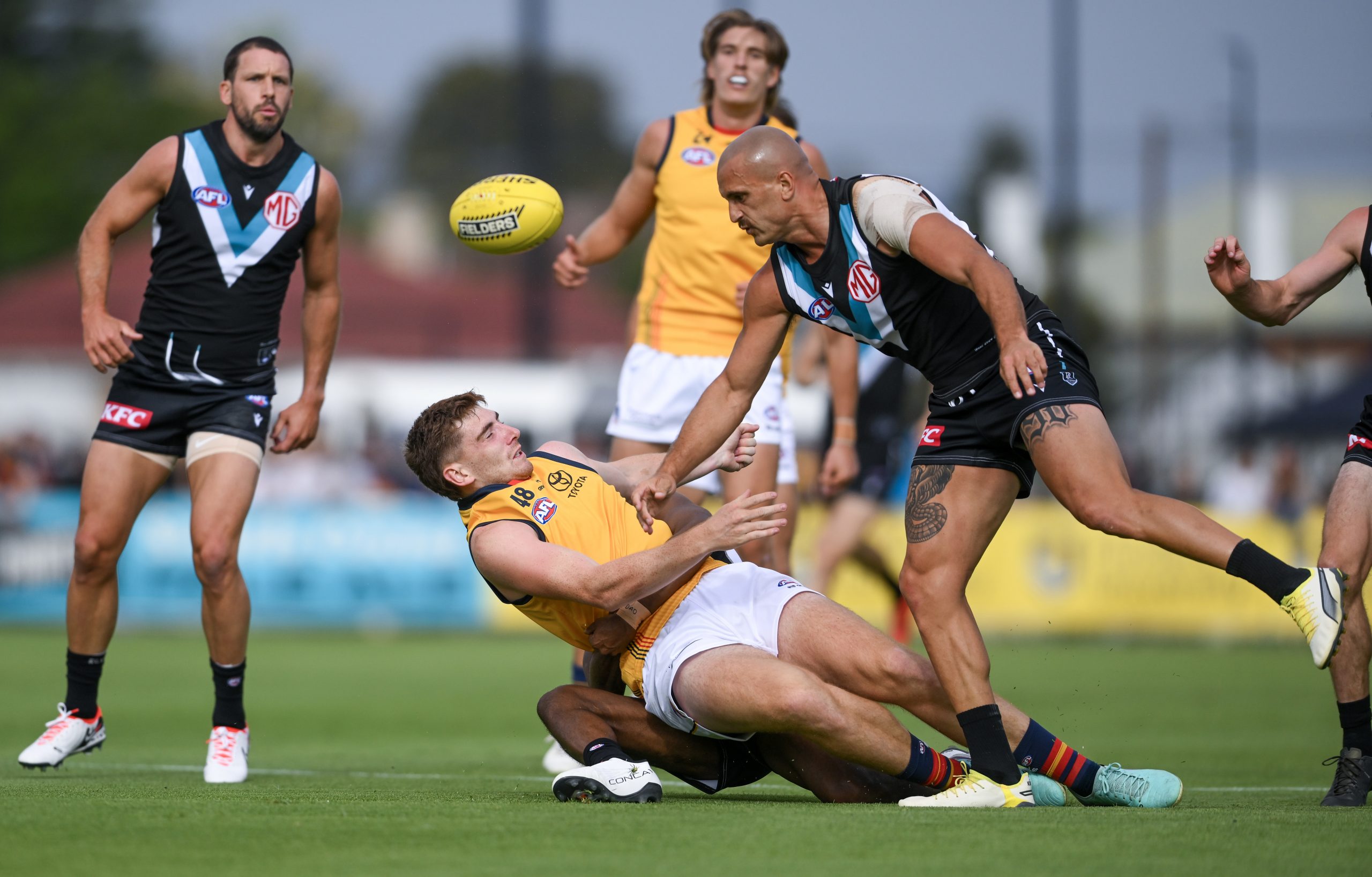 Mark Keane of the Crows  tackled by Willie Rioli of the Power and Sam Powell-Pepper of the Power causing a concussion during an AFL practice match.