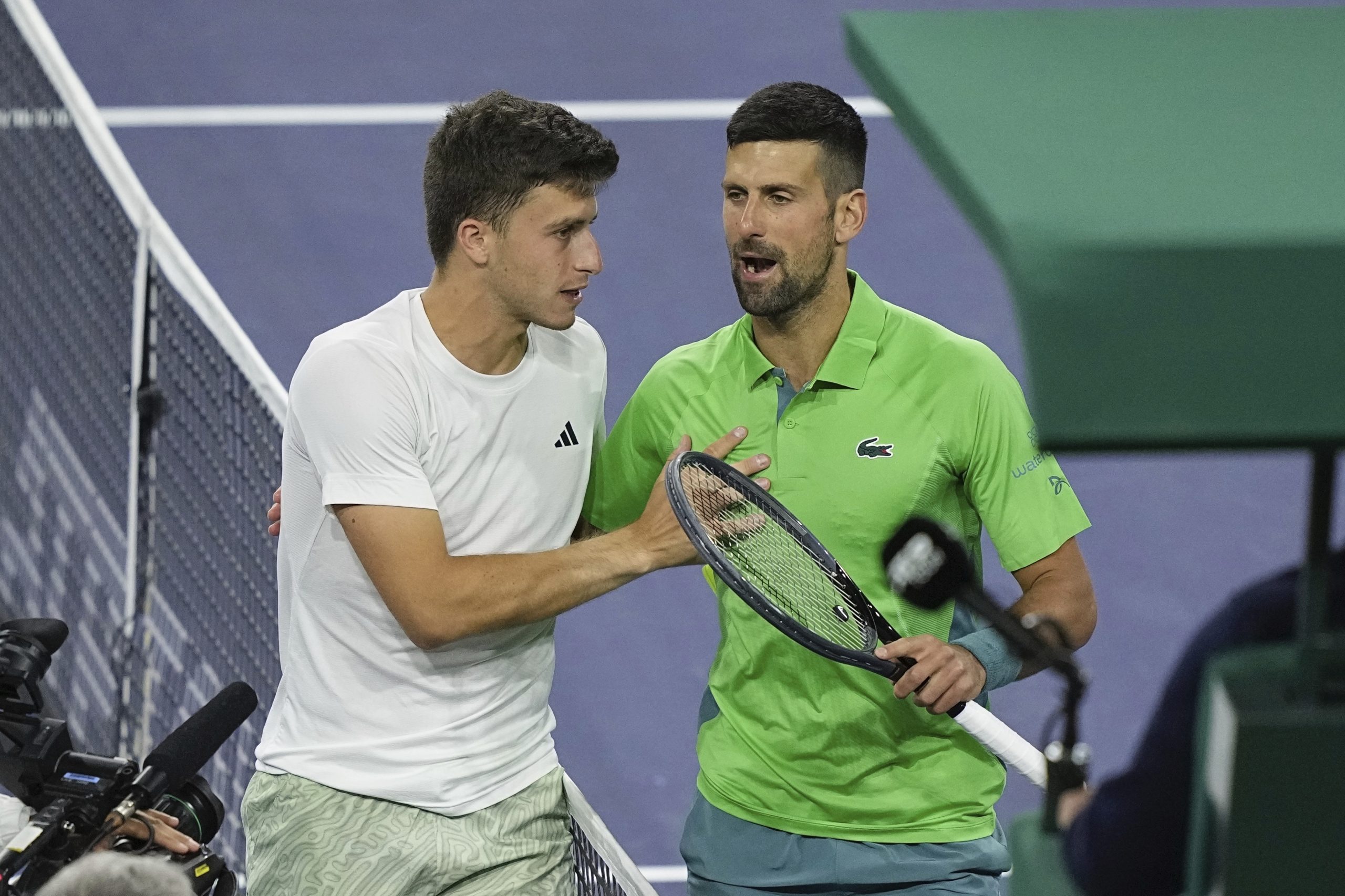Italy's Luca Nardi meets at the net with Novak Djokovic after winning his round of 32 match at Indian Wells.