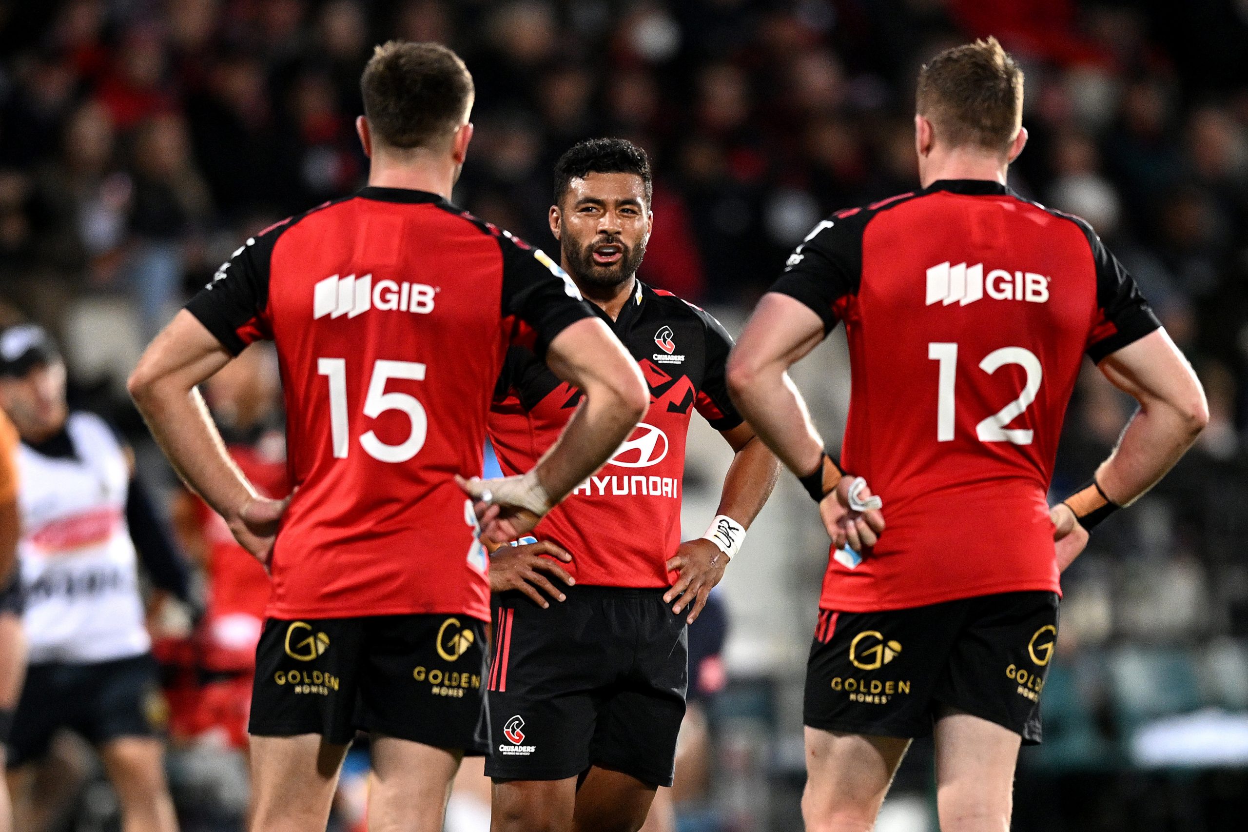 Richie Mo'unga of the Crusaders talks to Fergus Burke and Dallas McLeod of the Crusaders.