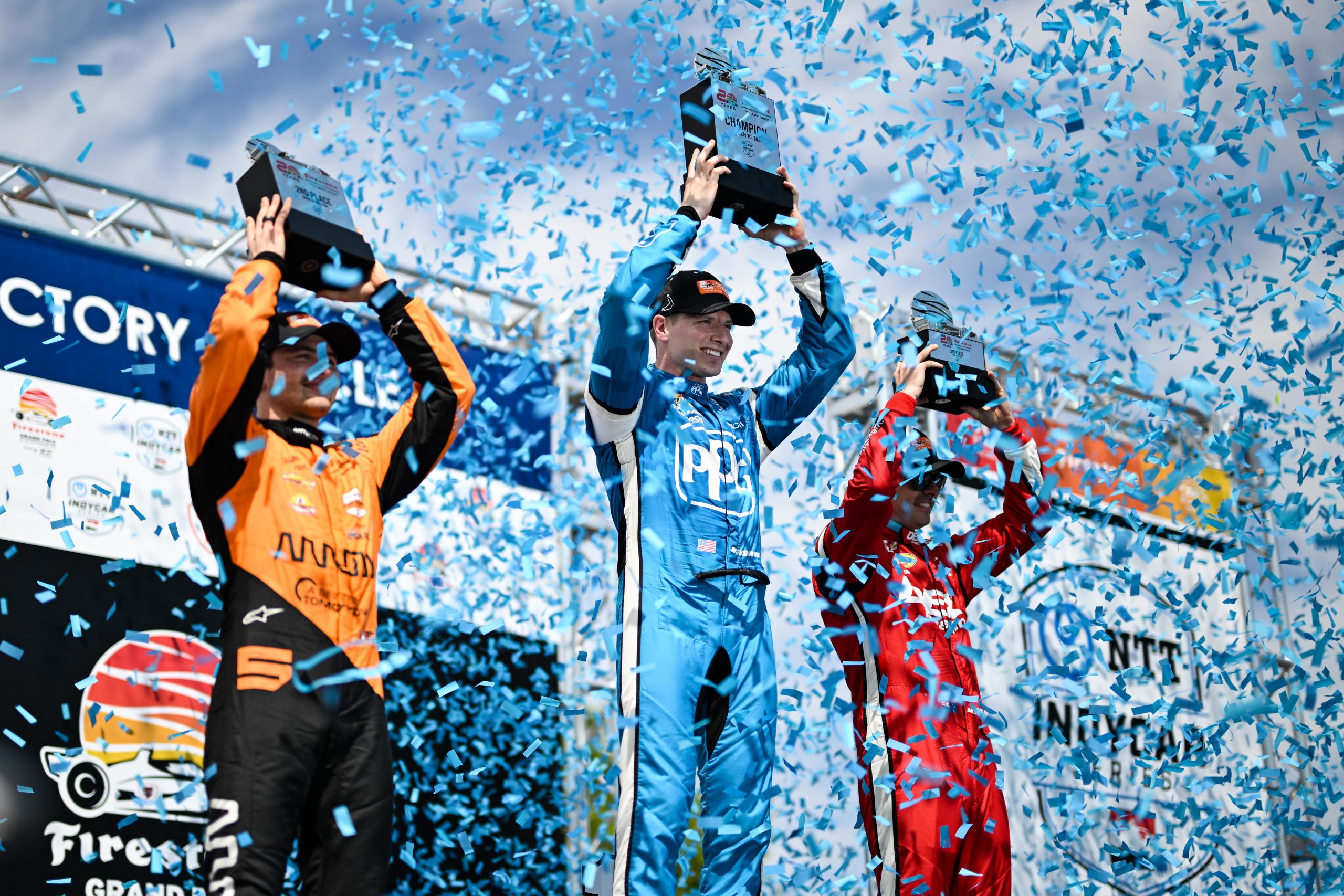 Runner-up Pato O'Ward (from left) celebrates on the podium with race winner Josef Newgarden and third place finisher Scott McLaughlin.