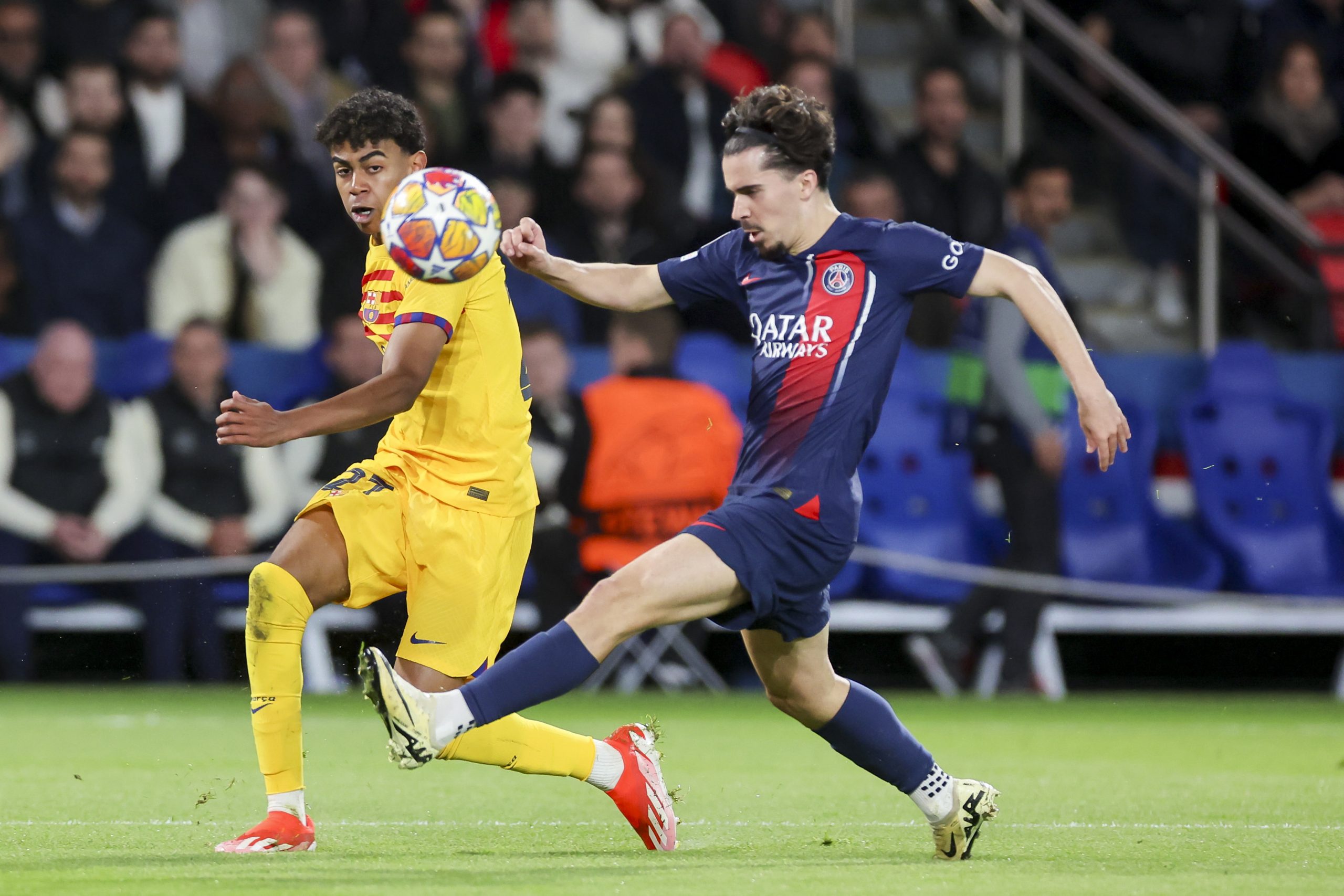 Lamine Yamal of Barcelona passes the ball alongside Vitinha of Paris Saint-Germain.