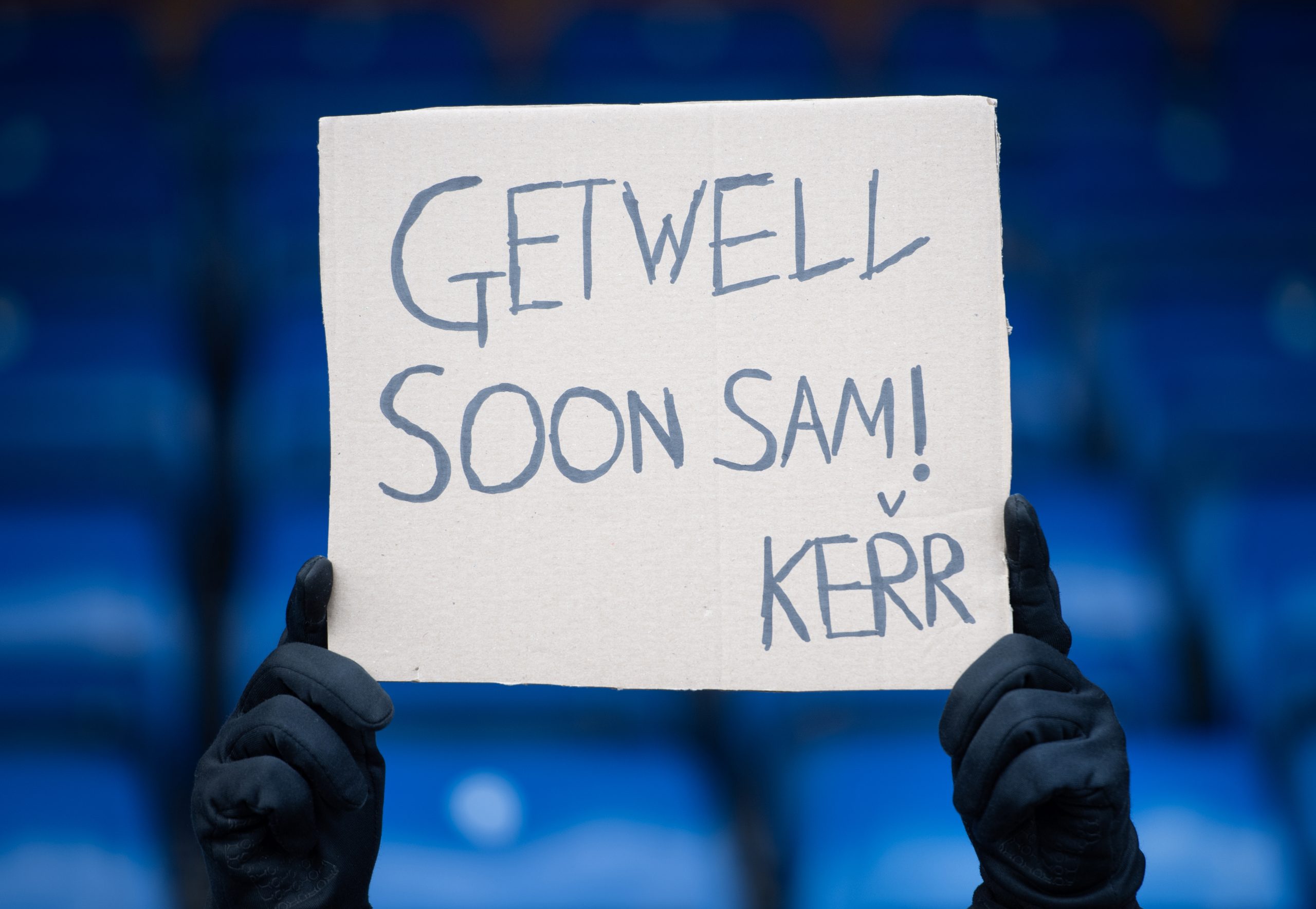 A fan holds up a banner wishing Sam Kerr to get well soon following her ACL injury.