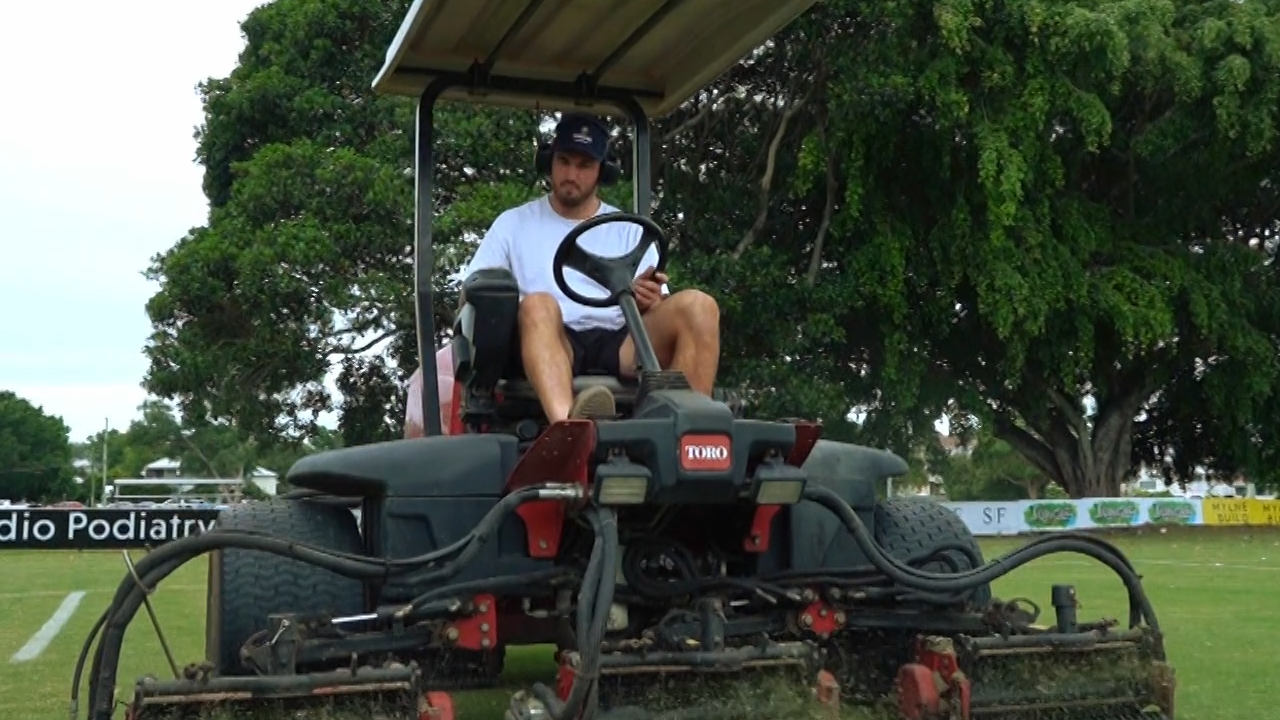 Liam Wright on the mower at Easts Rugby Union club in Brisbane.