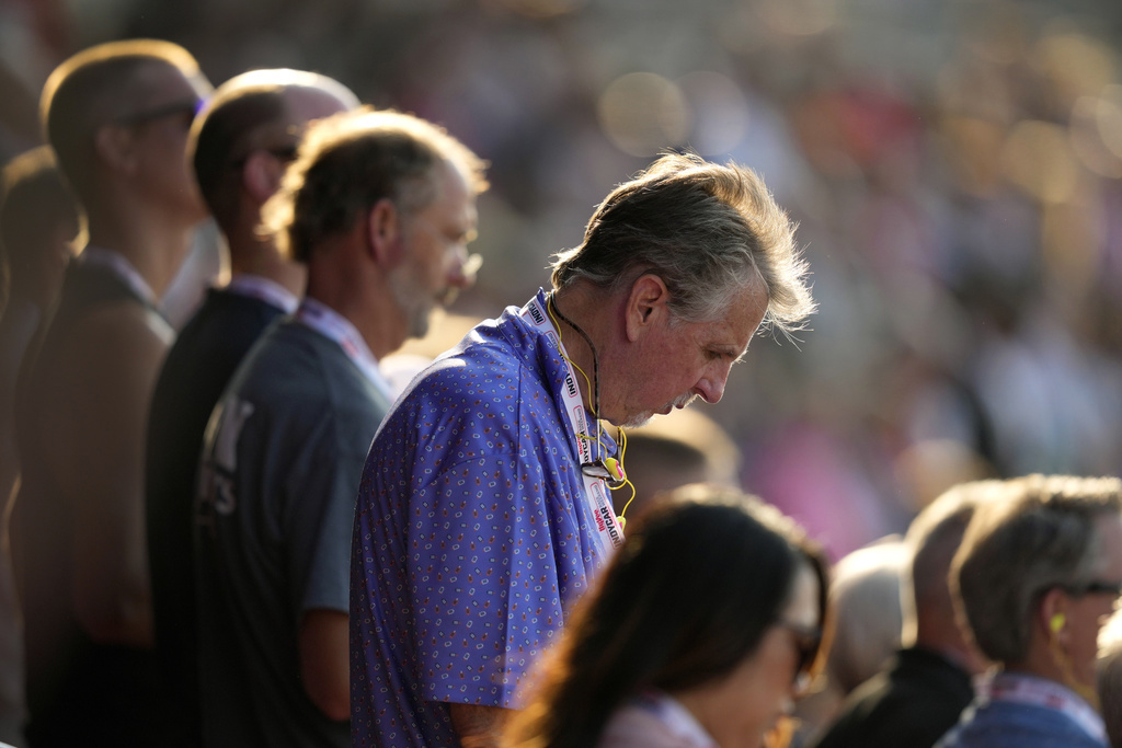 Fans bow their heads during a prayer for former President Donald Trump before an IndyCar race.