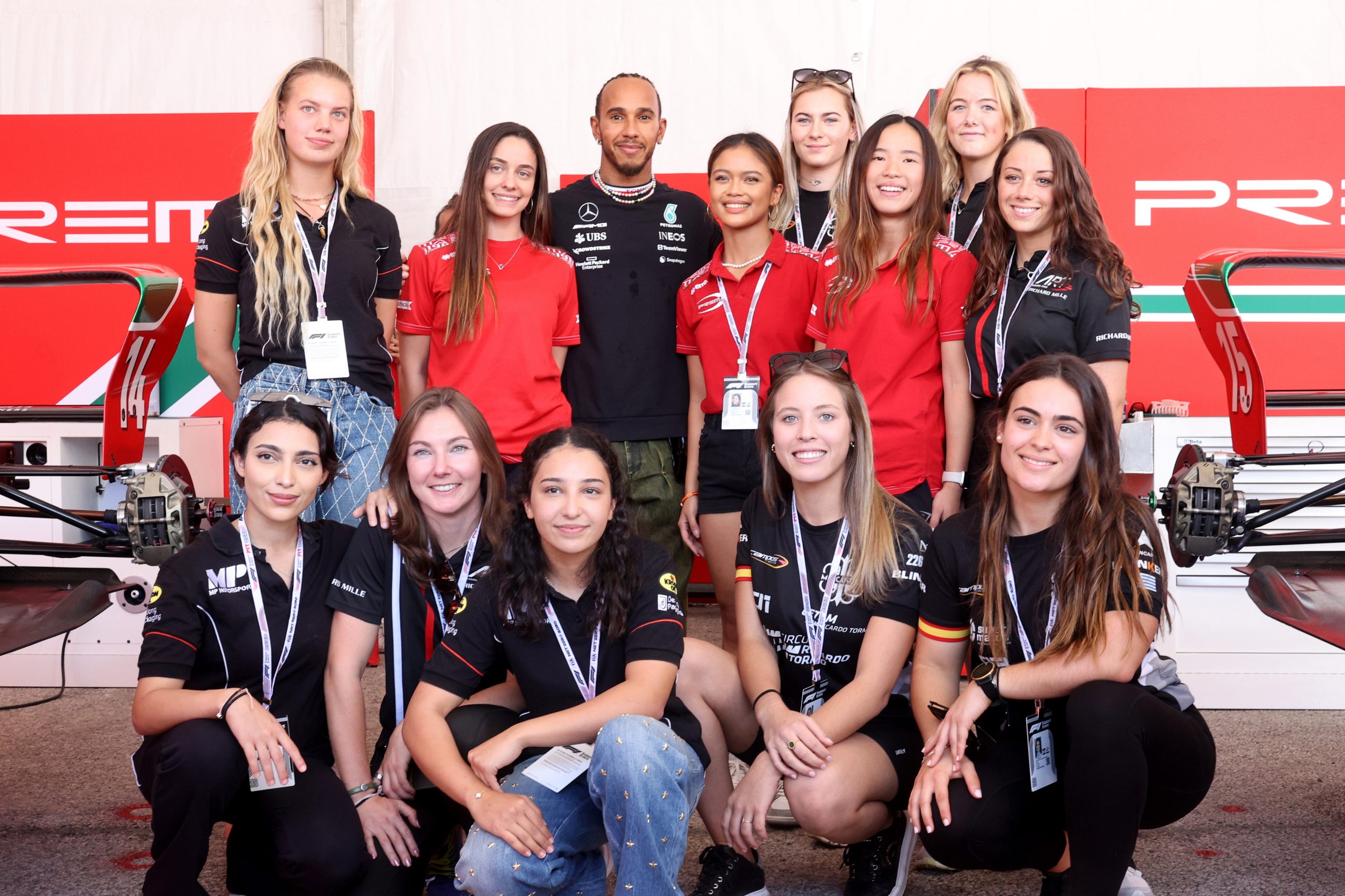 Lewis Hamilton poses for a photo with the F1 Academy drivers in the paddock ahead of F1 Academy round at Circuit of The Americas in 2023.