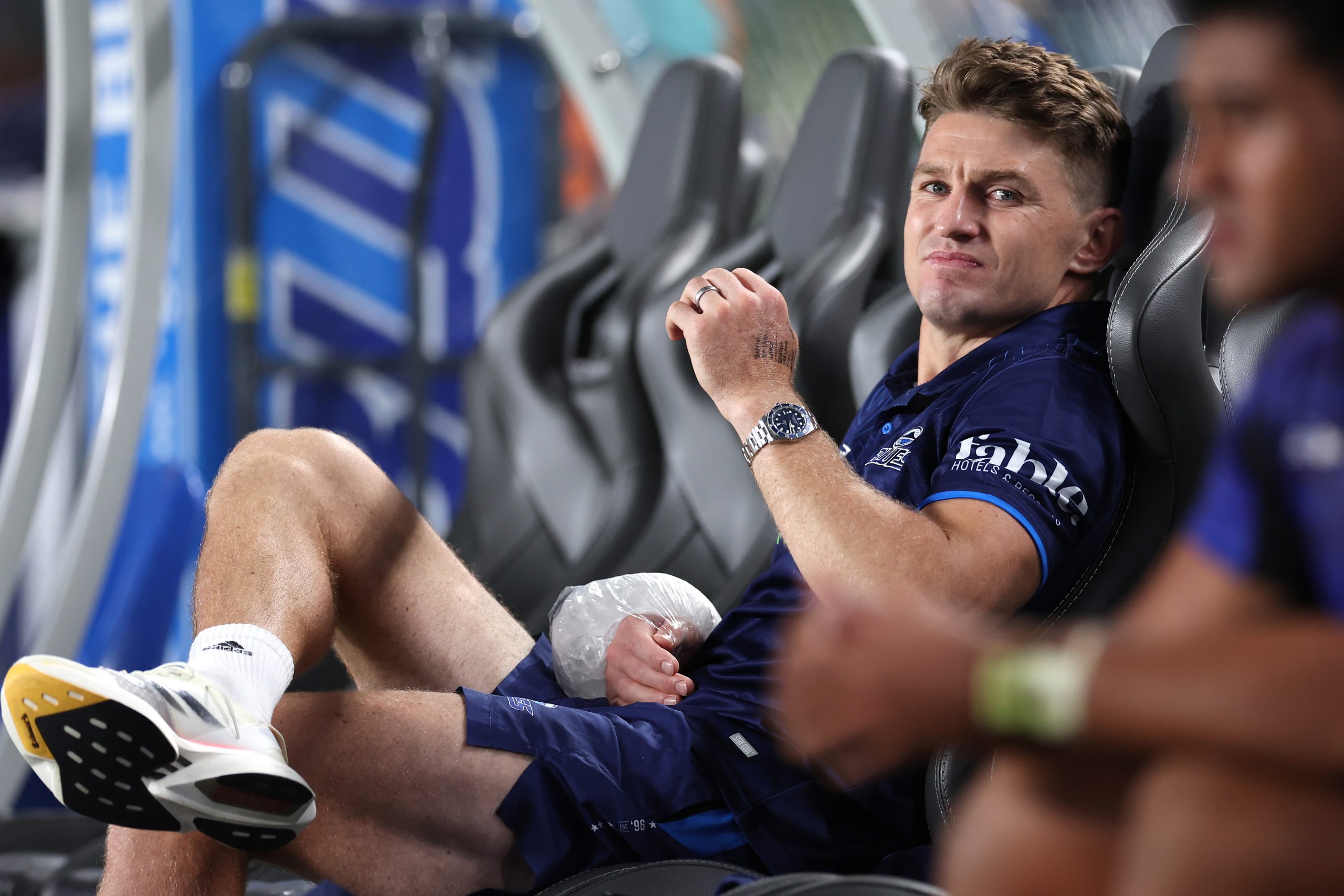 Beauden Barrett of the Blues sits on the bench with an icepack on his wrist.