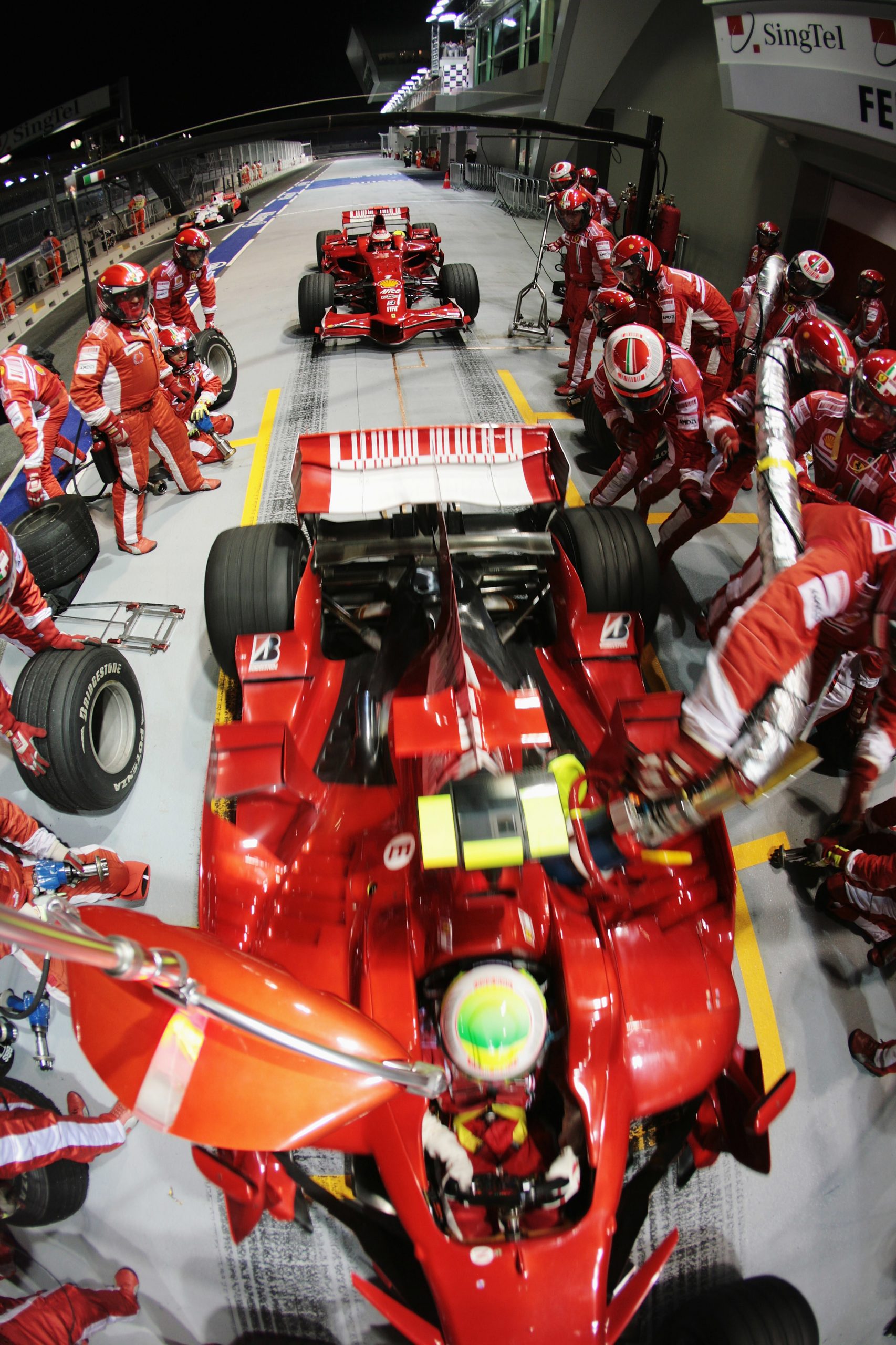 Felipe Massa of Brazil and Ferrari drives off with his refuelling hose still attached while Kimi Raikkonen of Finland and Ferrari waits behind to come in for his pitstop during the Singapore Formula One Grand Prix at the Marina Bay Street Circuit on September 28, 2008 in Singapore. The event is the first Formula One race to be held at night. (Photo by Mark Thompson/Getty Images)