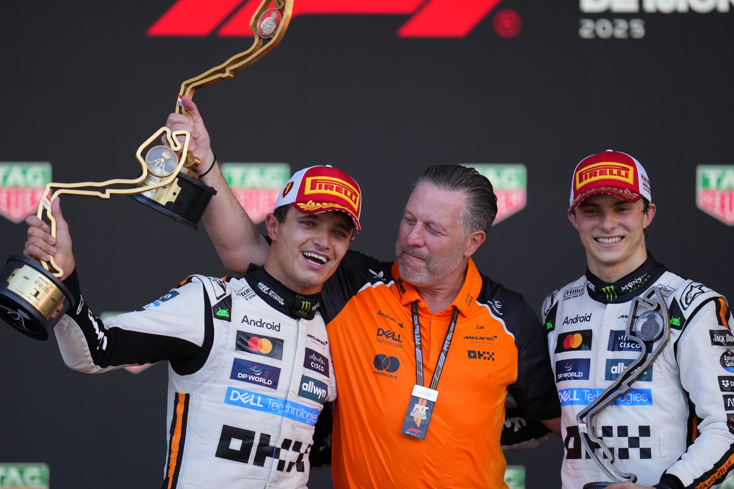 McLaren driver Lando Norris celebrates on the podium with Zak Brown, McLaren chief, and McLaren driver Oscar Piastri.