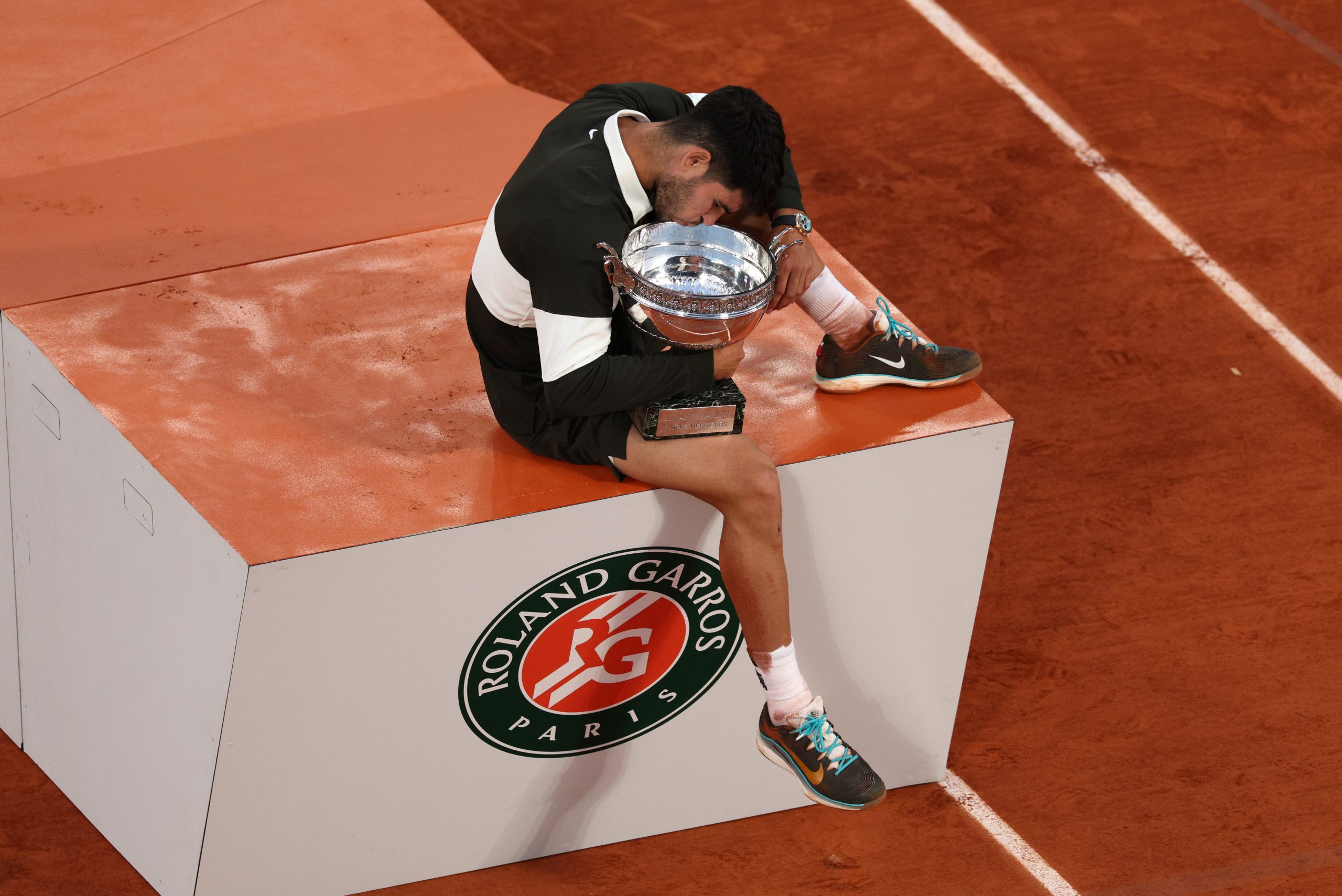 Carlos Alcaraz kisses the Coupe des Mousquetaires trophy.