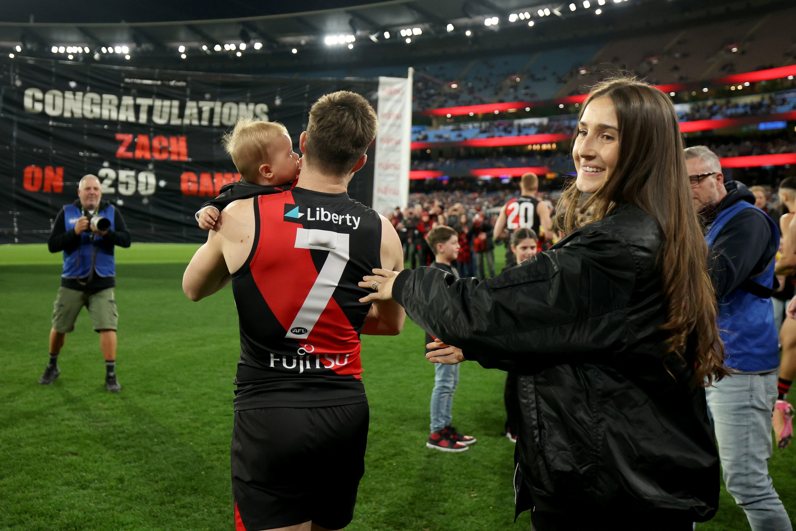 Zach Merrett of the Bombers is congratulated by his wife Alexandra and son Jude during his 250th game.