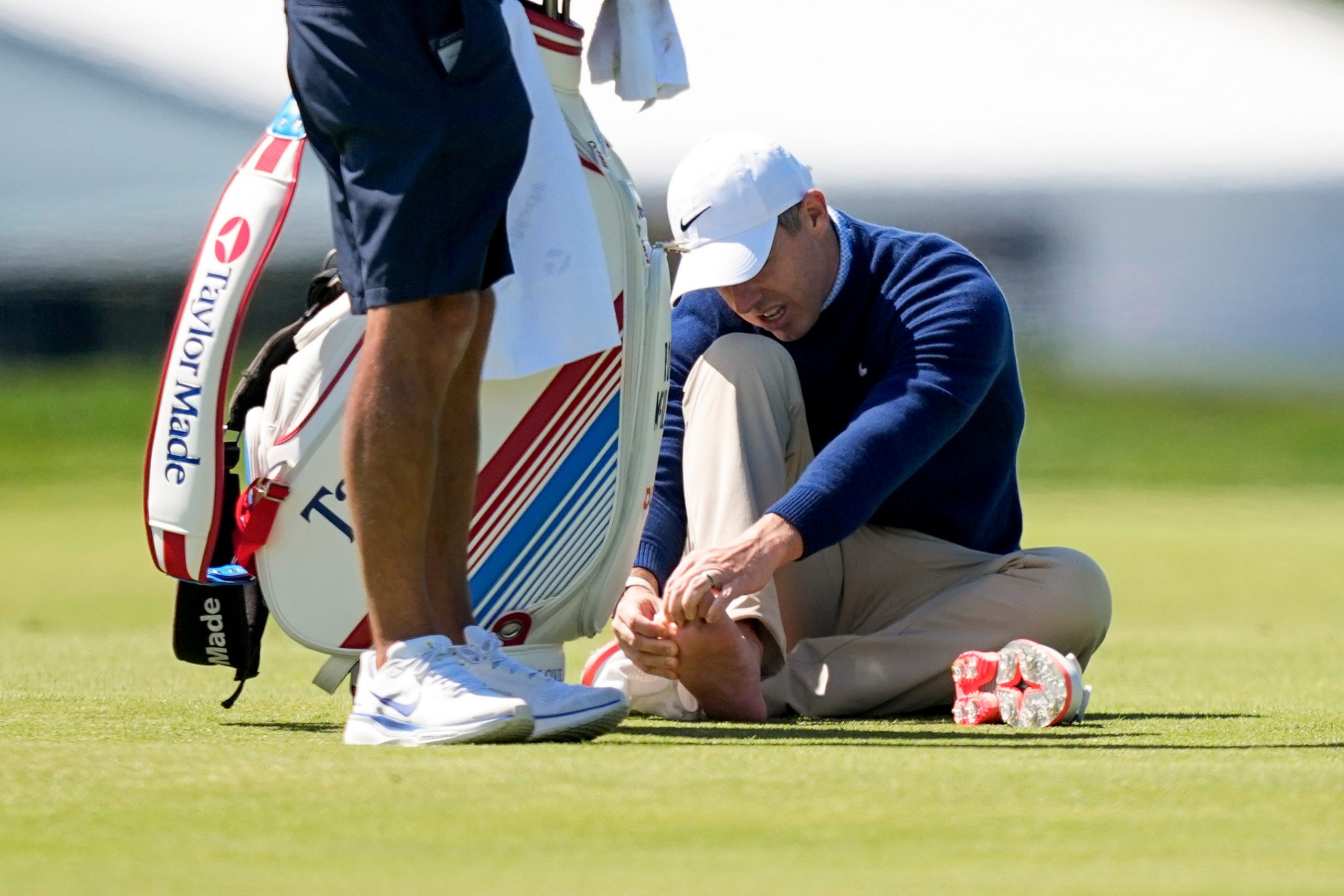 Rory McIlroy, of Northern Ireland, attends to his foot on the third fairway during a PGA Championship golf tournament practice round at Aronimink Golf Club, Tuesday, May 12, 2026, in Newtown Square, PA. (AP Photo/Matt Slocum)